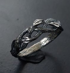 a silver ring sitting on top of a black table next to a piece of wood