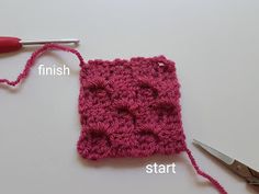 the crochet square is being worked on with scissors