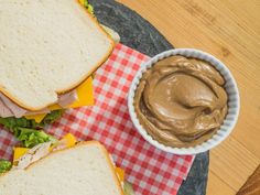 two sandwiches with peanut butter and lettuce sit on a plate next to a bowl of dip