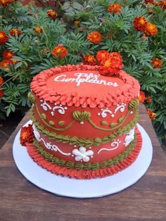 a red cake sitting on top of a white plate next to some orange and green flowers