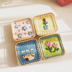 four small square trays with flowers and animals on them, sitting on a table