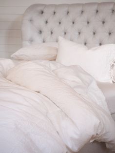 an unmade bed with white linens and pillows