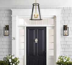 a black front door with two planters on either side and one light hanging from the ceiling