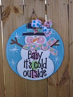 a baby it's cold outside sign hanging on the side of a wooden fence