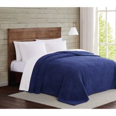 a blue and white bedspread on a bed in a room with wooden headboard