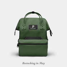 a green backpack sitting on top of a white surface with the words restocking in may