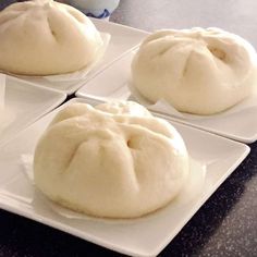 four white plates topped with buns on top of a table