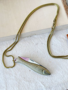 a fish shaped object is sitting on the floor next to a chain and pencils