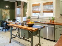 a kitchen with green walls and white flooring has a wooden table in the center