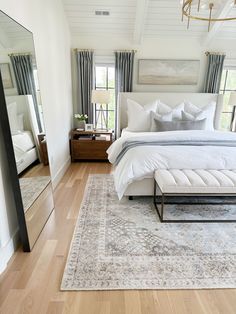 a large bed sitting in a bedroom on top of a hard wood floor next to a mirror