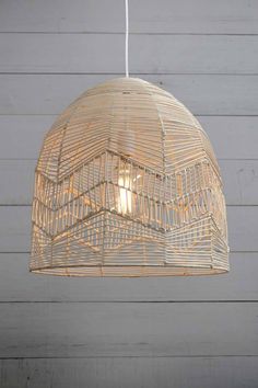 a light fixture hanging from the ceiling in front of a wooden wall with white planks