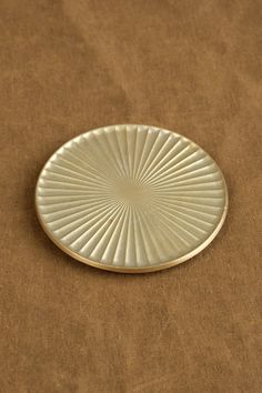 a small white plate sitting on top of a brown cloth covered table next to a wall