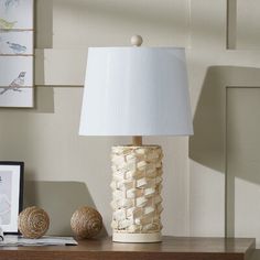 a white lamp sitting on top of a wooden table next to a framed photo and two balls