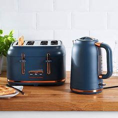 two toasters sitting on top of a wooden counter next to a potted plant