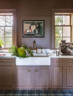 a kitchen with two windows and a sink in front of the window is an art piece