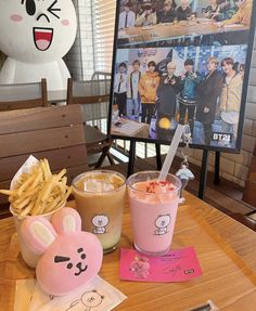 a table topped with drinks and food next to a stuffed animal figure on top of a wooden table