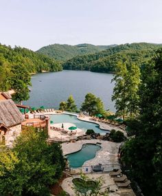 an aerial view of a pool and hot tub surrounded by wooded area with mountains in the background