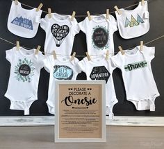 baby onesuits are hung on clothesline and hanging in front of a chalkboard