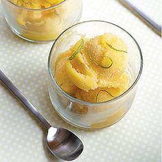 two small glass bowls filled with food on top of a table next to spoons