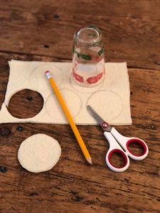 some scissors and other crafting supplies on a wooden table with a jar full of water