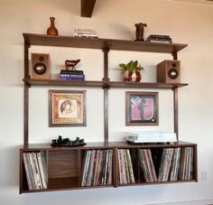 an entertainment center with shelves and records on the wall, including two stereo's