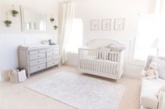 a baby's room with a white crib, dresser and chair in it