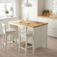 a kitchen island with two chairs next to it and a table in front of it