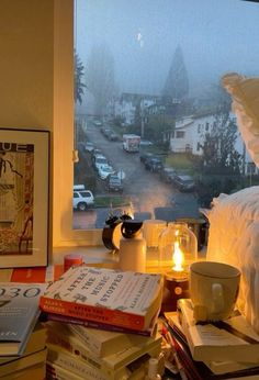 a window sill filled with lots of books next to a cup and lamp on top of a table