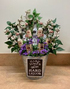 a metal bucket filled with lots of liquor bottles and purple flowers next to a sign that says hard times hard liquor