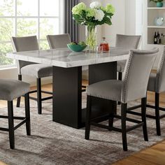 a dining room table with chairs and a vase on top of it in front of a window