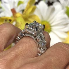 a close up of a person's hand holding a ring with a diamond on it