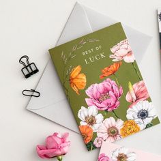 two greeting cards with flowers on them next to a pair of scissors and pencils