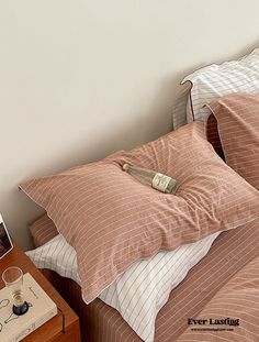 a bed with two pillows and a cell phone on the side table next to it