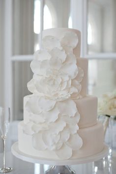 a three tiered white wedding cake with flowers on top