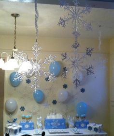 a table topped with blue and white desserts under a snowflake hanging from the ceiling