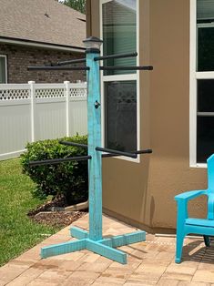 a blue chair sitting on top of a brick patio next to a tall wooden pole