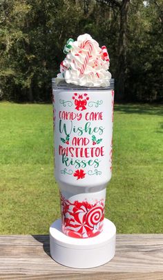 a cup filled with whipped cream and candy canes on top of a wooden table