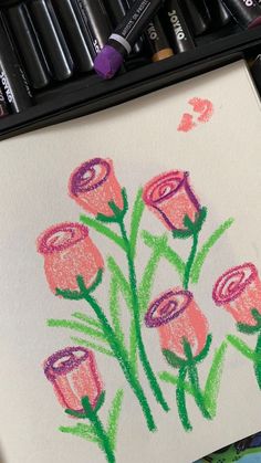 some crayons are laying on top of a paper with flowers drawn on it