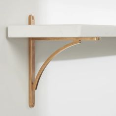 a white shelf with two wooden brackets on it