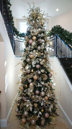 a decorated christmas tree in the middle of a hallway with stairs leading up to it