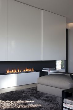 a modern living room with a fireplace in the center and white cabinets on either side