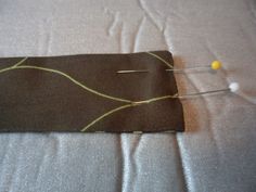 the sewing needle is being used to sew something on top of the fabric with two pins