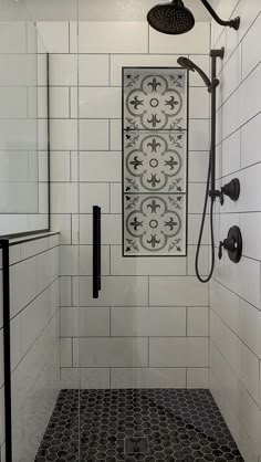 a bathroom with black and white tile on the walls, shower head, and hand held faucet