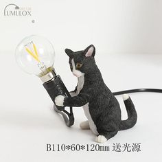 a black and white cat figurine holding a light bulb