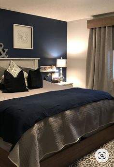 a bedroom with blue walls and white bedding, black and silver decor on the headboard