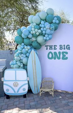 there is a surfboard and some balloons in front of a sign that says the big one