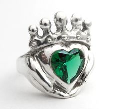 "Claddagh rings are Celtic promise rings, and this emerald ring is modern, unique and can be personalized to create the perfect birthstone jewelry gift for weddings, engagements anniversaries and birthdays. My Claddagh rings are all handmade in my home studio. I set out to create a unique Claddagh design that really shows love and devotion in the hands, heart and crown.  You can even get stones set in the crown! Message for a quote.  The hands are there for friendship,  The heart is there for love.  For loyalty throughout the year,  The crown is raised above  How to can wear your Claddagh Ring: - On the right hand, the heart pointed away, means you are free as the wind. - On the right hand, the heart pointed toward you, then you are spoken for. - On the left hand, the heart pointed towards Heart-shaped Emerald Jewelry With Birthstone, Heart-shaped Emerald Birthstone Jewelry, Green Promise Jewelry For Valentine's Day, Silver Heart Ring For May Birthstone Gift, Emerald Jewelry For Valentine's Day Gift, Heart Cut Emerald Jewelry For May Birthstone, Emerald Jewelry For Anniversary On Valentine's Day, May Birthstone Heart Ring Gift, Green Heart Ring For May Birthstone Gift