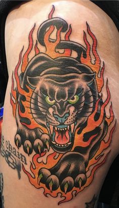 a man with a tattoo on his thigh that has a tiger and flames around it