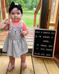 a baby standing on a porch next to a sign that says only 9 months old and i'm already a queen of drama, but it still counts 20lbs