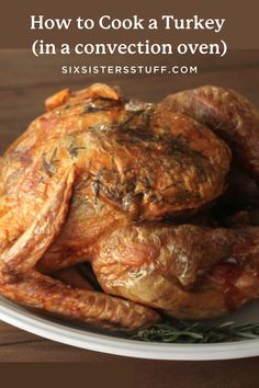 a whole chicken on a white plate with rosemary